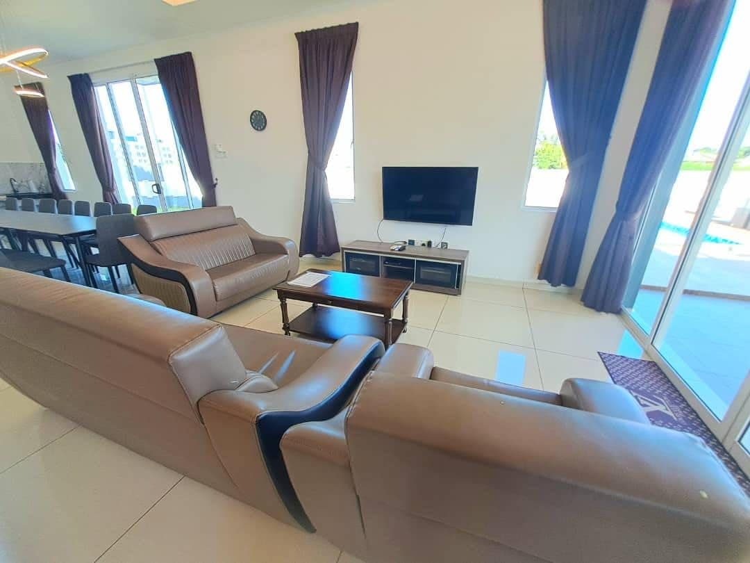 A living room with a sofa, coffee table, TV, and a dining area with chairs and a table.
