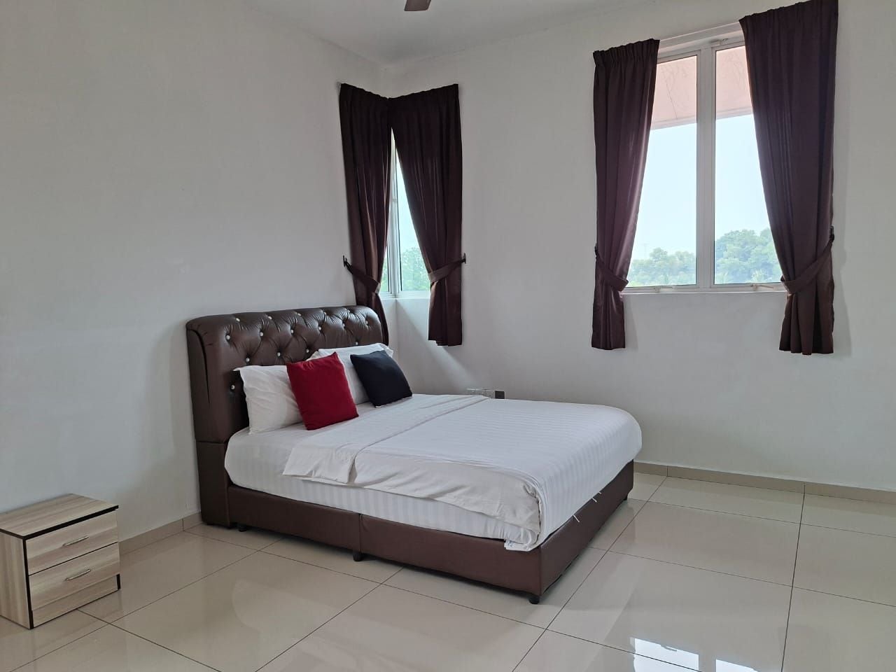 A bedroom with a bed, curtains, a bedside table, and a window.