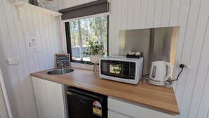 Angolo cottura compatto dotato di forno a microonde, macchina del caffè e lavandino.