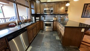 Una cocina moderna con armarios de madera, electrodomésticos de acero inoxidable y suelo de baldosas de piedra.