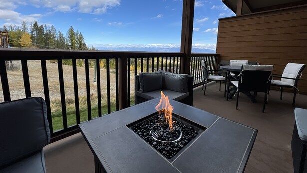 Una terraza con hogar, asientos exteriores y vistas a montañas.