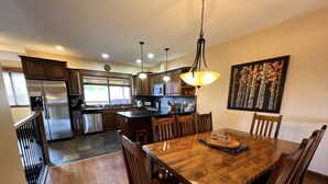 Una cocina amplia con electrodomésticos modernos, un comedor con mobiliario de madera y un gran ventanal que proporciona luz natural.