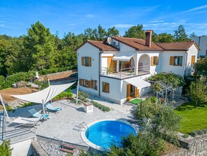 Uma casa de dois andares com piscina, área de estar externa e jardim.