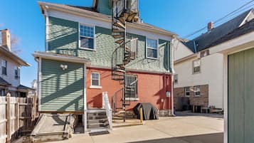 A two-story building with a central staircase, a covered outdoor area, and a wooden fence.