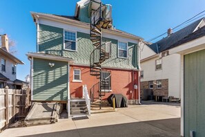 A two-story building with a central staircase, a covered outdoor area, and a wooden fence.