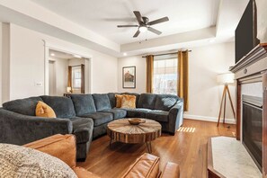 A living room with a sectional sofa, a round coffee table, and a fireplace.