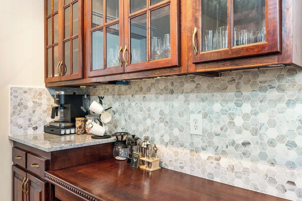 Una cocina con armarios de madera, una cafetera y un salpicadero de azulejos hexagonales.