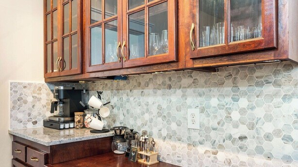 A kitchen with wooden cabinets, a coffee machine, and a hexagonal tile backsplash. - The Pioneer - Charming Home Walkable to Streetcar! (Kansas City)