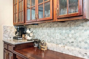 A kitchen with wooden cabinets, a coffee machine, and a hexagonal tile backsplash.