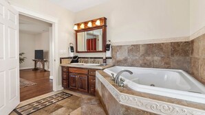 Ein Badezimmer mit einer großen Badewanne, einem Doppelwaschbecken und einem Spiegel mit Beleuchtung darüber.
