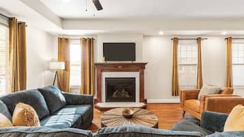 Un salon doté d’une cheminée, d’un ventilateur de plafond et d’un téléviseur à écran plat fixé au mur.