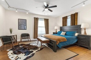 A bedroom with a bed, bedside tables, a ceiling fan, and a window with curtains.