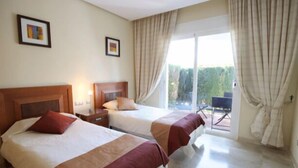A hotel room with two beds, a balcony, and a view of greenery. - Loasis, Luxueux et Calme 2 Chambres au Bord du Golf de la Cala, vue Montagnes (Mijas)