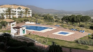 A resort with a swimming pool, palm trees, and a view of distant mountains. - Loasis, Luxueux et Calme 2 Chambres au Bord du Golf de la Cala, vue Montagnes (Mijas)