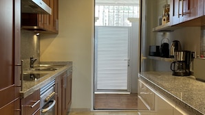 A modern kitchen with wooden cabinets, stainless steel appliances, and a large window with blinds. - Loasis, Luxueux et Calme 2 Chambres au Bord du Golf de la Cala, vue Montagnes (Mijas)