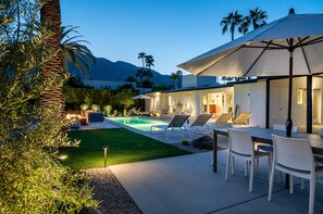 Relax and socialize in this outdoor living space with a pool, lounge chairs, and dining area.
