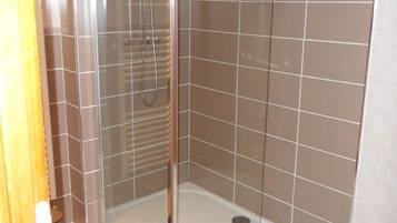Une cabine de douche fermée par des parois en verre, avec un sol et des murs carrelés.