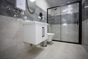 A modern bathroom with a white vanity, a toilet, and a glass-enclosed shower area. - Bright House Apart (Ortaca)