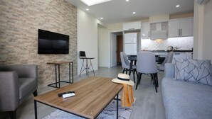 Un salon moderne avec un téléviseur à écran plat, une table basse en bois et un canapé gris.