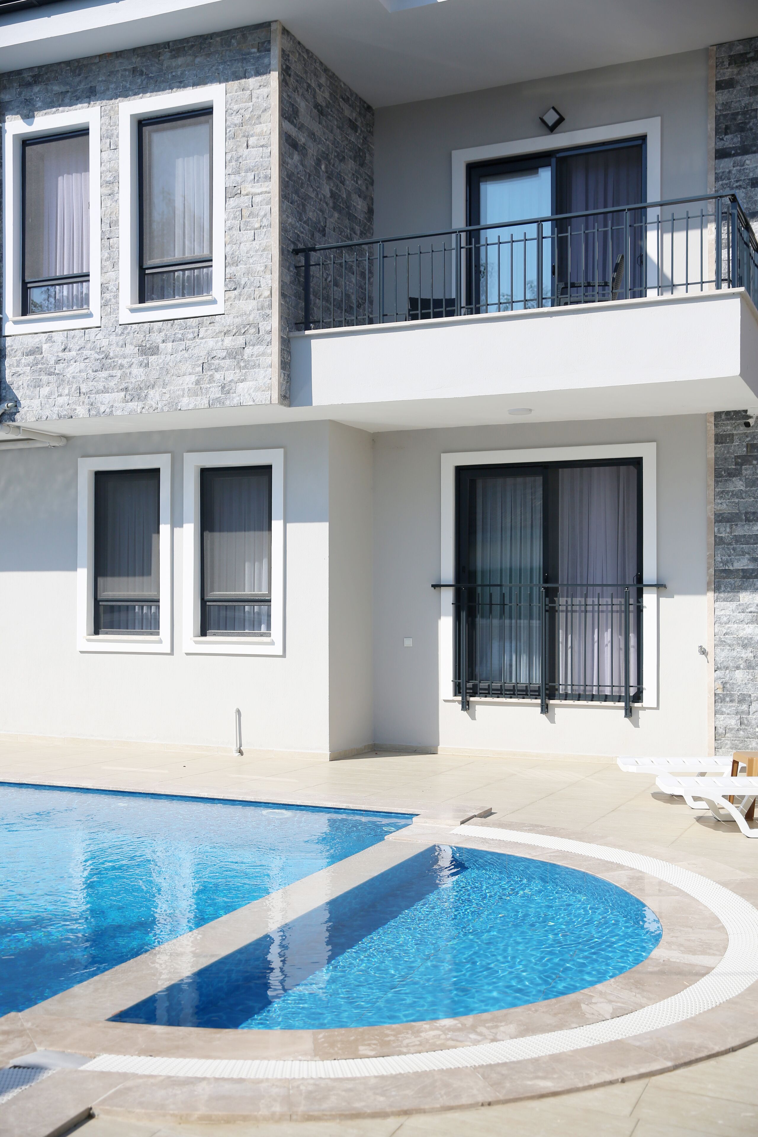 A modern building with a pool, balconies, and large windows.