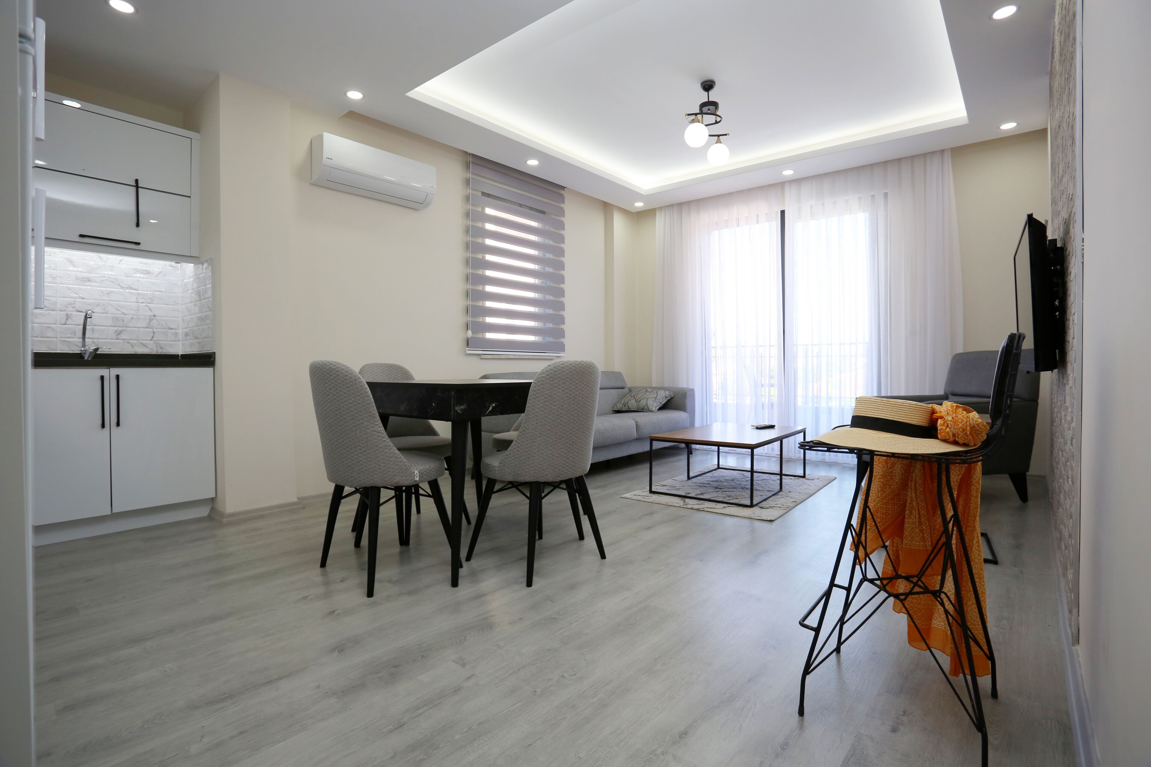 A modern living room with a dining area, a sofa, and a TV.