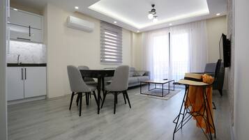 A modern living room with a dining area, a sofa, and a TV.