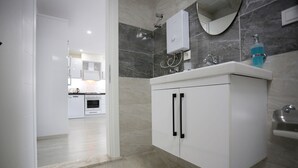Une salle de bain moderne avec un meuble-lavabo blanc, une douche et un miroir.