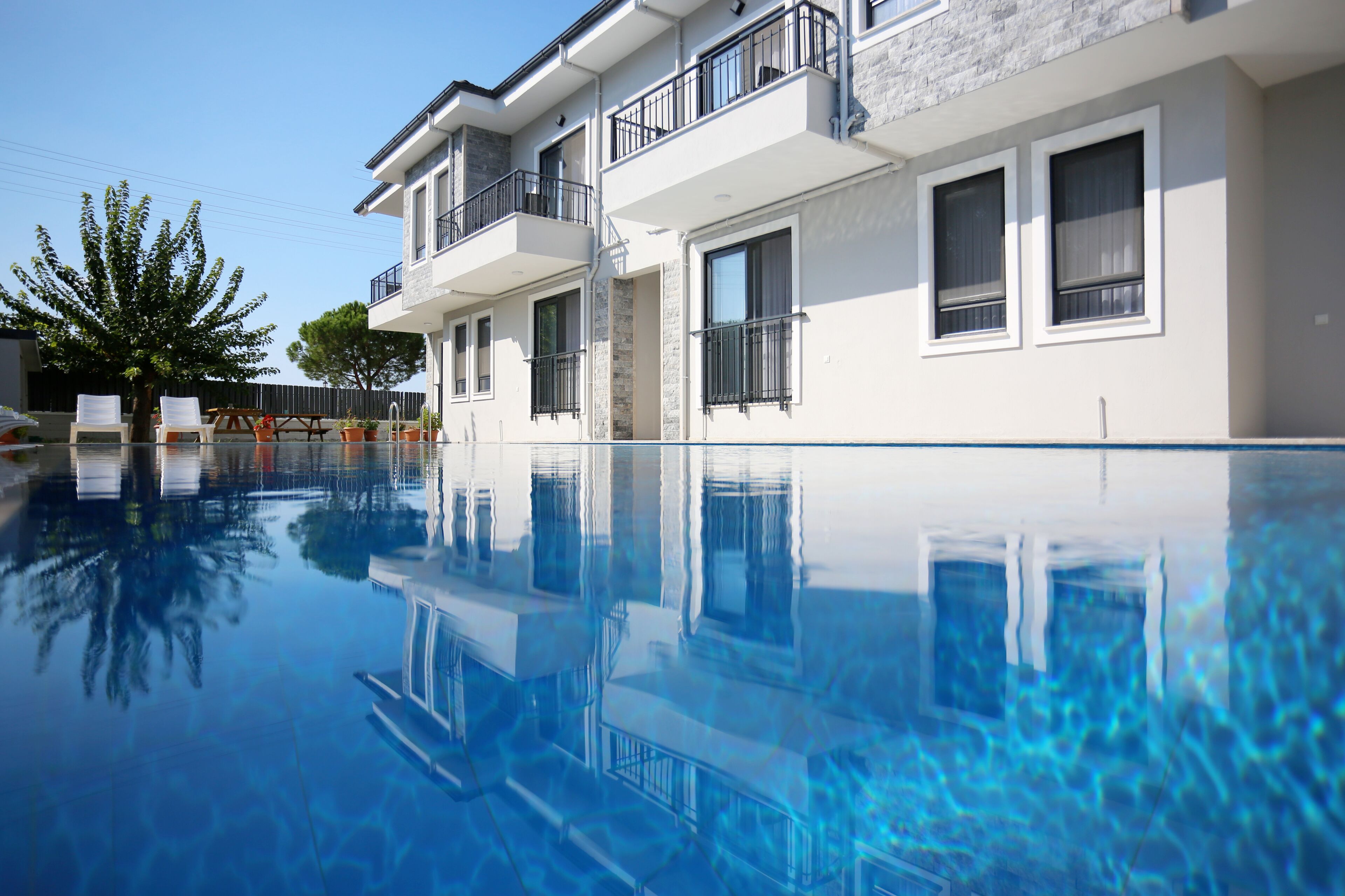A modern building with a swimming pool, balconies, and a clear blue sky.
