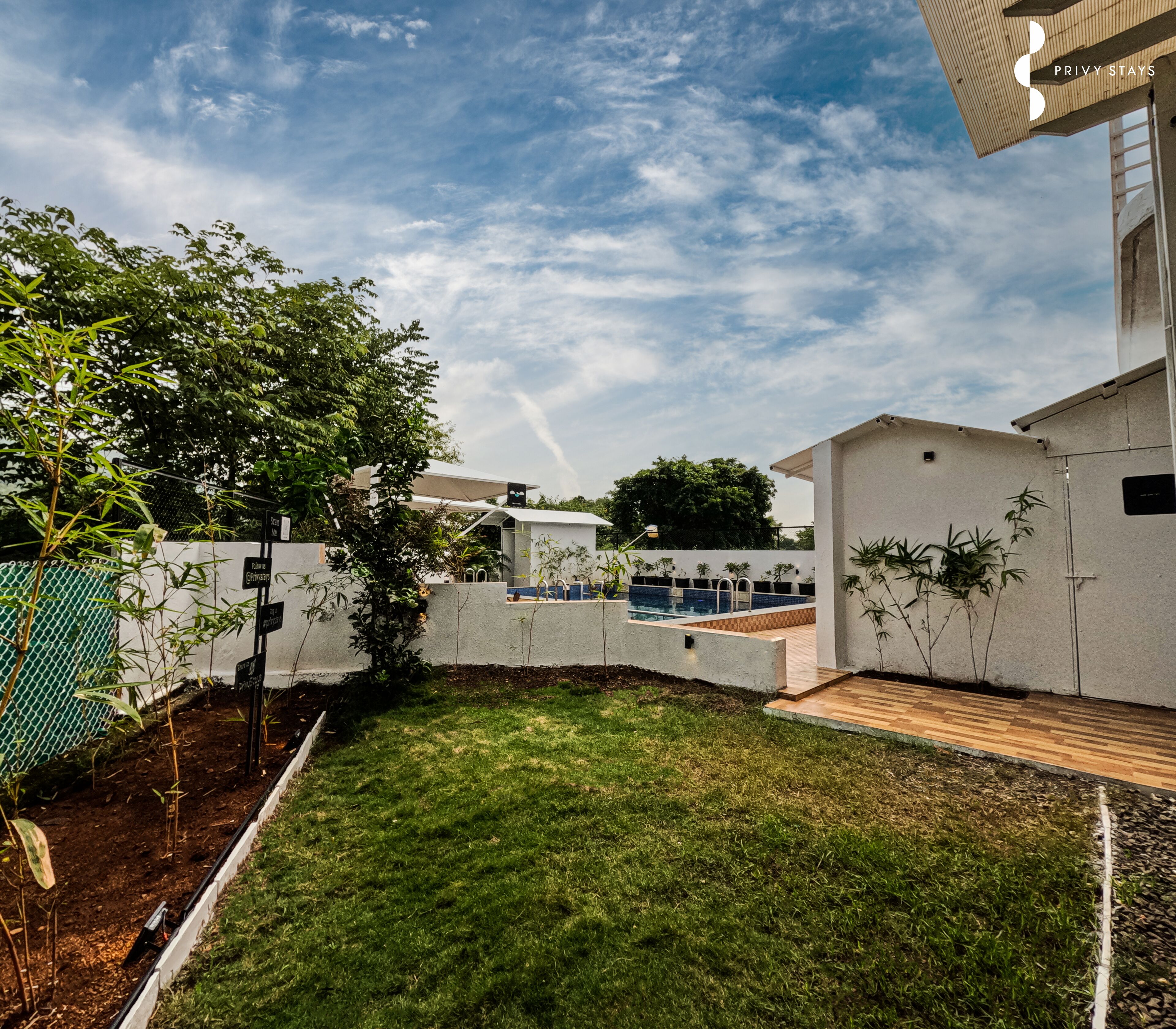 A modern residential area with a swimming pool, a well-maintained lawn, and a white building with a flat roof.