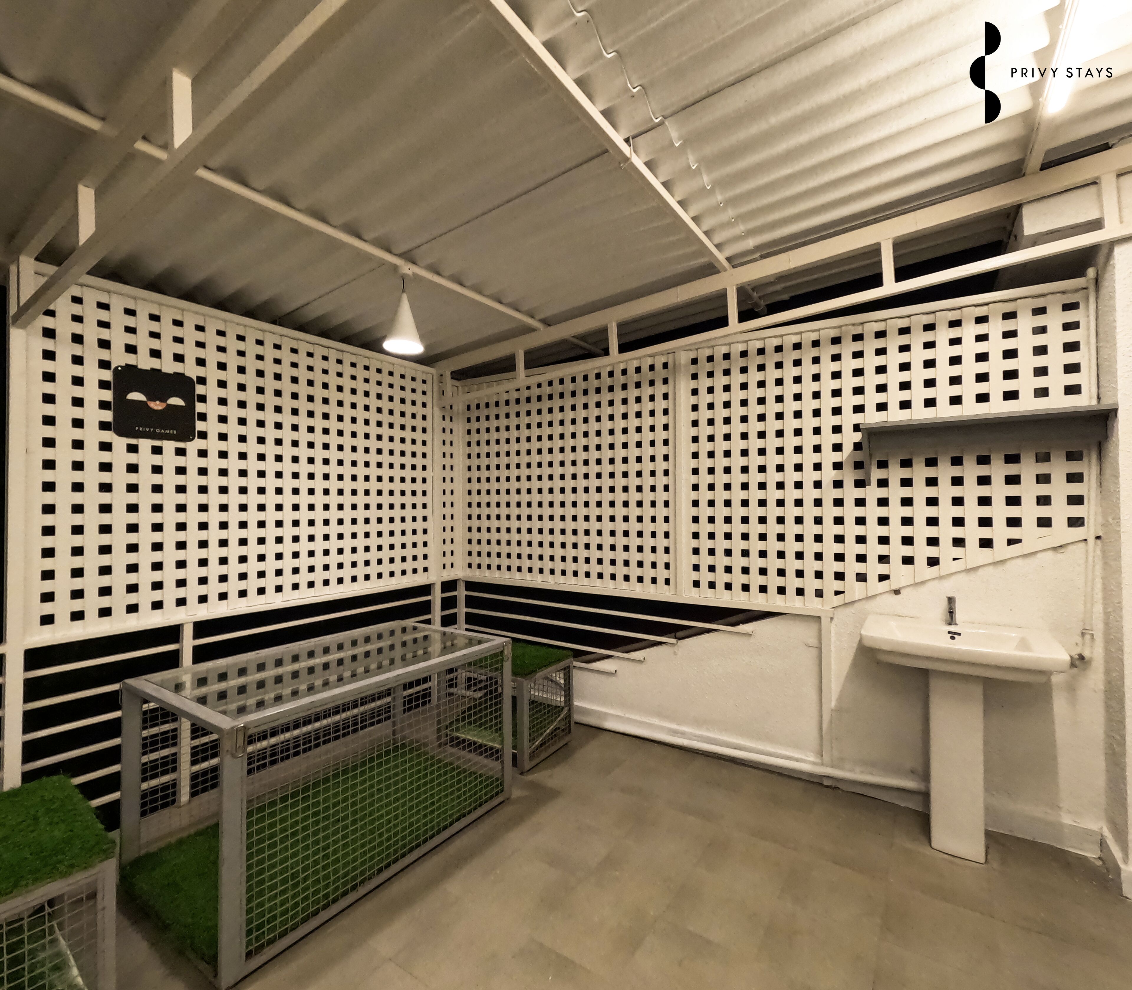 Una habitación con techo blanco, divisiones de malla metálica, un lavabo y una pequeña señal negra.