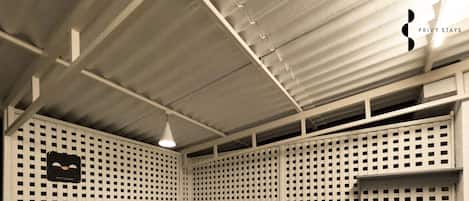 Una habitación con techo blanco, divisiones de malla metálica, un lavabo y una pequeña señal negra.