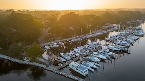 A marina with boats docked, surrounded by trees and a clear sky. - Bung-a-flo Tiny Bohemian Designed Floating Home w/ 360 Waterfront Views (Arnold)