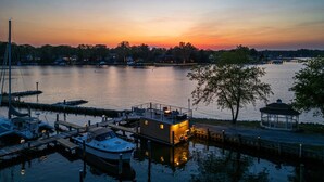 A marina with docked boats, a small building with a balcony, and a gazebo by the water. - Bung-a-flo Tiny Bohemian Designed Floating Home w/ 360 Waterfront Views (Arnold)