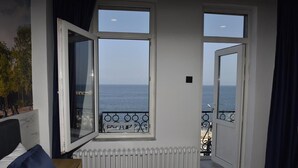A bedroom with a large bed, a radiator, and a view of the sea through open windows. - Bella Otel Mudanya  (Mudanya)