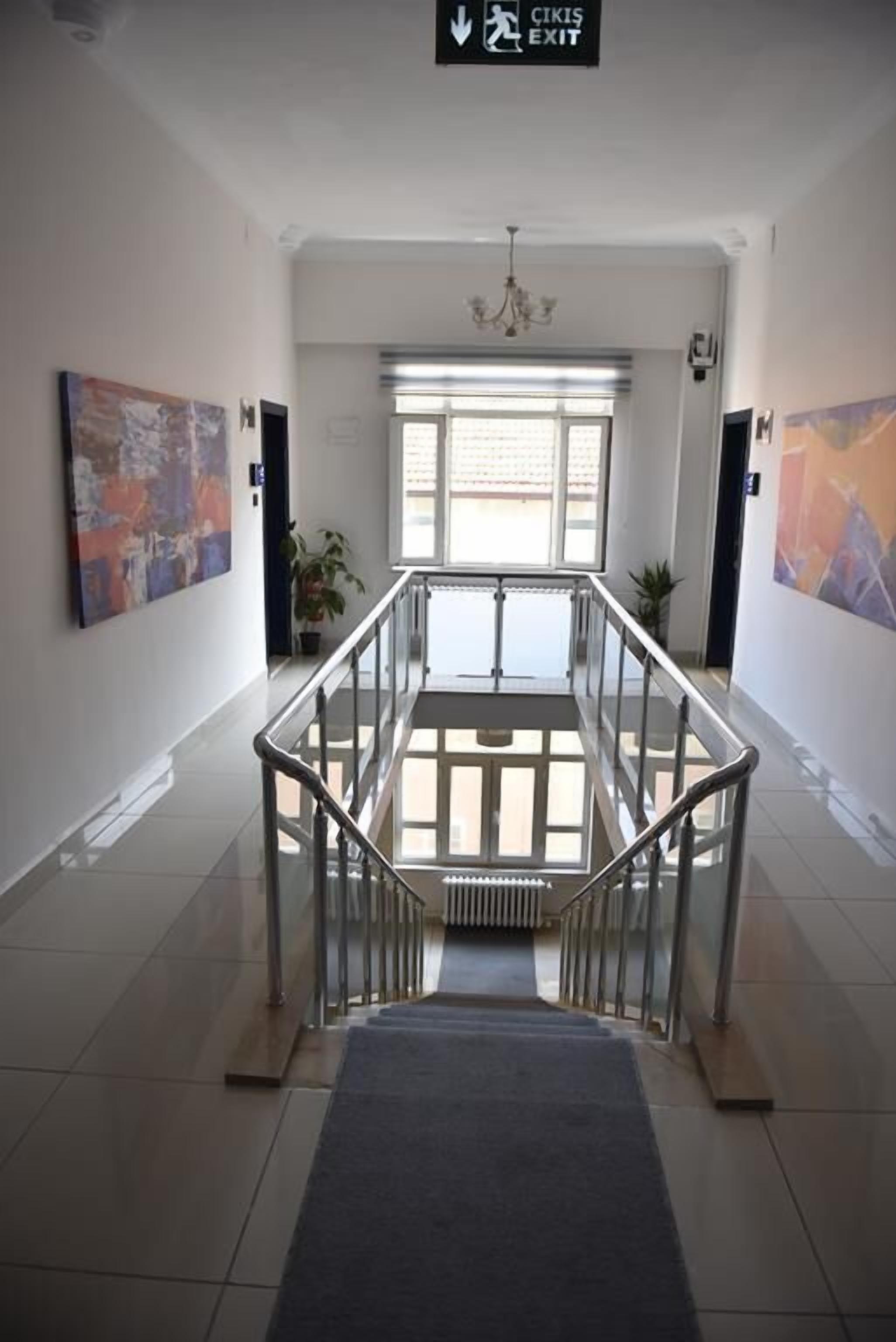 A hotel lobby with a staircase, artwork on the walls, and a chandelier.