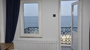 A room with a view of the sea through a window and an open door leading to a balcony with a railing. - Bella Otel Mudanya  (Mudanya)