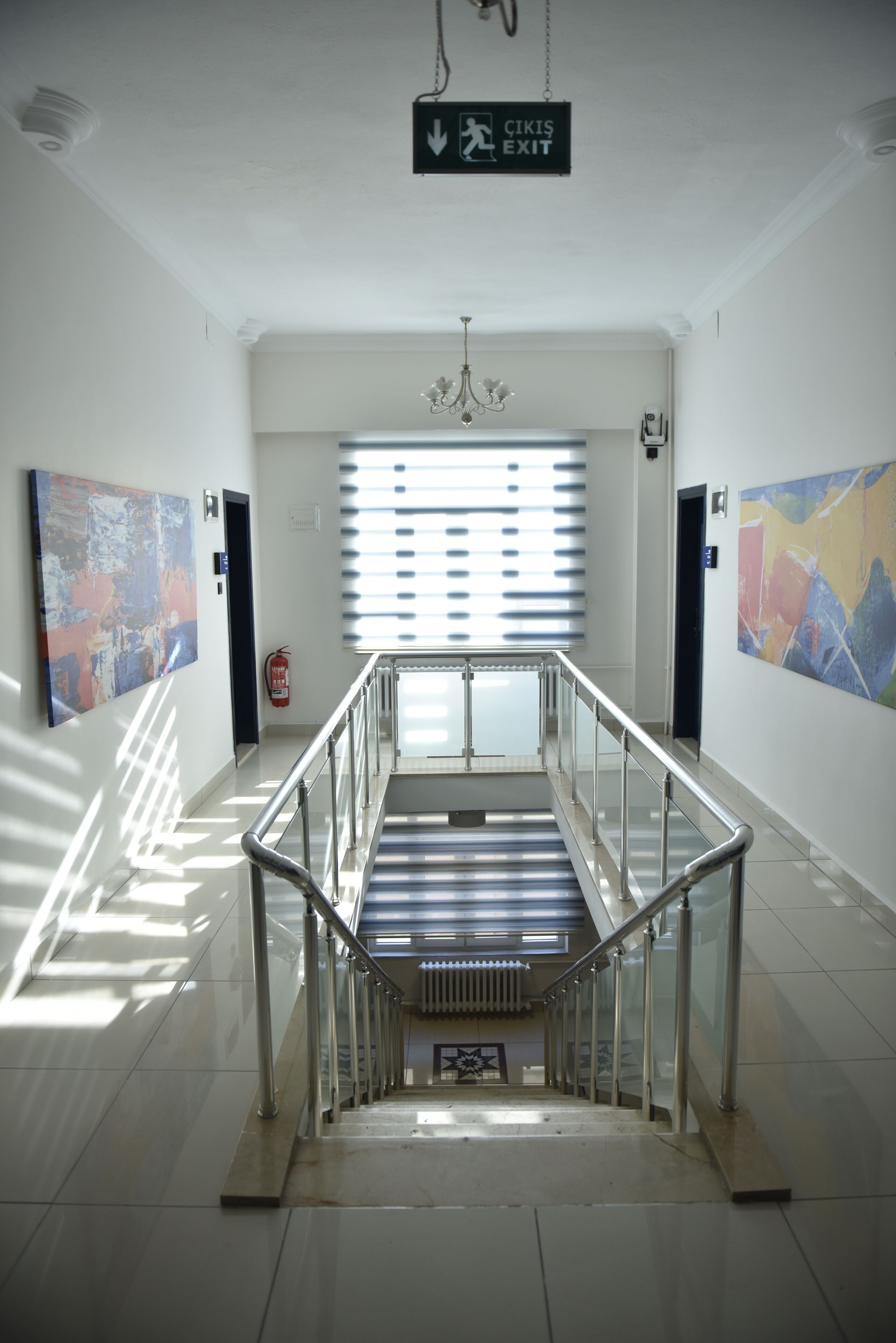 A clean, modern interior with a staircase, glass railings, and artwork on the walls.