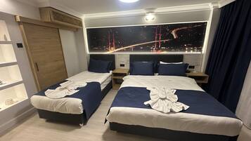 Habitación de hotel con dos camas, vista nocturna de un puente y un ventanal grande.