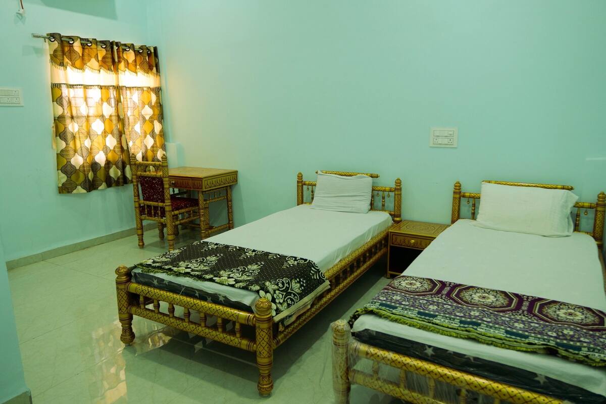 A room with two wooden beds, a small table, and a chair.
