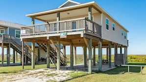 A two-story house with a balcony, wooden deck, and a staircase leading to the upper floor. - Ocean Pearl - Ultimate Beach & Boat Watch Escape! (Surfside Beach)