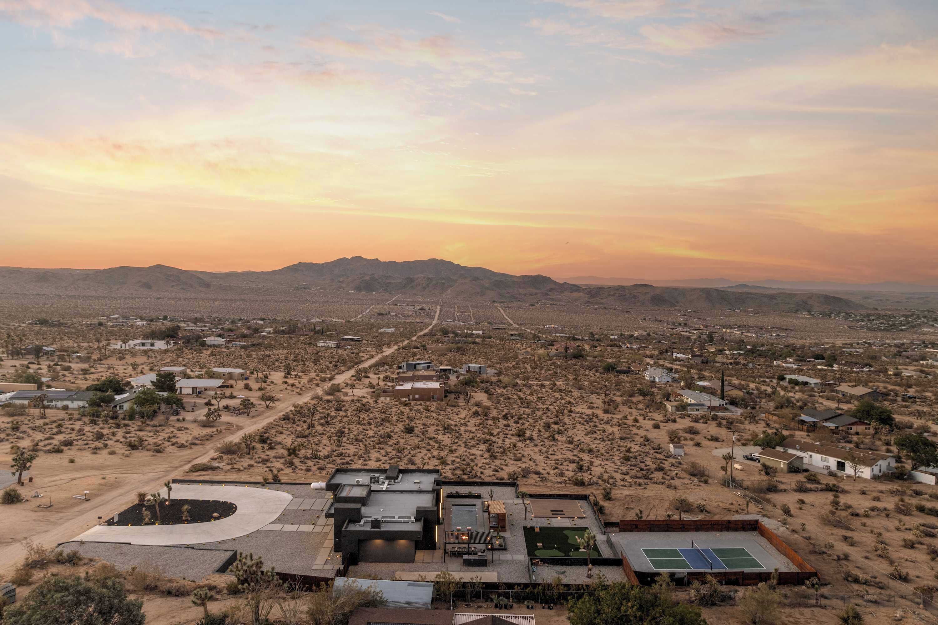 A desert landscape with scattered buildings, a clear sky, and distant mountains.