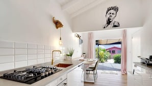 Une cuisine moderne avec des meubles blancs, une cuisinière à gaz et un coin repas comprenant une table et des chaises.