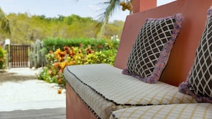 Une terrasse en bois avec un banc rembourré et un coussin décoratif.