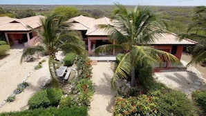 Un hôtel de style bungalow doté d’une cour sablonneuse, de palmiers et offrant une vue sur le paysage environnant.