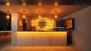 Zona de bar amb disseny modern, que inclou un taulell central, prestatges amb ampolles i lluminàries penjants.
