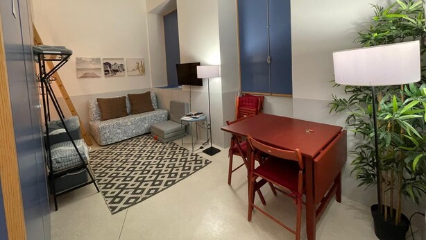 Un ambiente compatto con un divano, un tavolo da pranzo, una TV e una lampada.