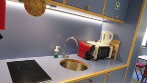 Una cucina compatta con lavandino, forno a microonde, bollitore ed un tostapane.
