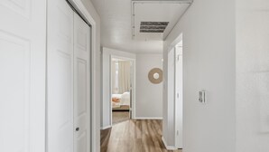 A hallway with white walls, a wooden floor, and a ceiling vent. - Renovated 3BR with Yard & Mountain Views (Rio Rancho)