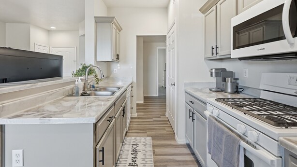 A modern kitchen with white cabinets, a black range hood, and a stainless steel sink. - Renovated 3BR with Yard & Mountain Views (Rio Rancho)