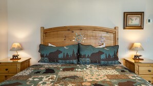 Una camera da letto con testiera in legno, coprip letto trapuntato, due lampade da comodino e un quadro appeso al muro.